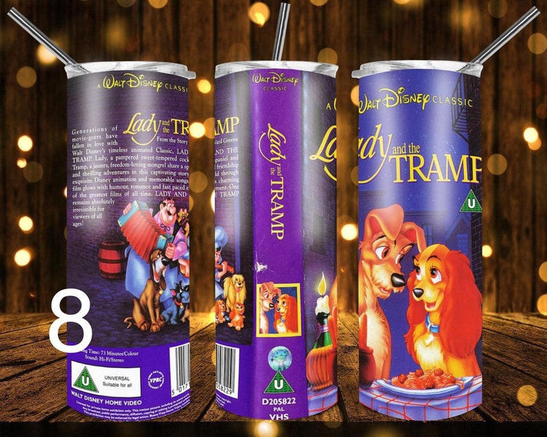 Puede incluir: Un vaso de acero inoxidable morado y blanco con un dise&ntilde;o de la cinta VHS de La Dama y el Vagabundo. El dise&ntilde;o incluye el t&iacute;tulo de la pel&iacute;cula, un logotipo de Universal y una imagen de Lady y Tramp compartiendo un plato de espaguetis.