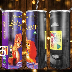 Puede incluir: Un vaso de acero inoxidable con un dise&ntilde;o inspirado en una cinta VHS vintage de la pel&iacute;cula de Disney La Dama y el Vagabundo. El dise&ntilde;o presenta el t&iacute;tulo de la pel&iacute;cula, una clasificaci&oacute;n U y una escena de la pel&iacute;cula.