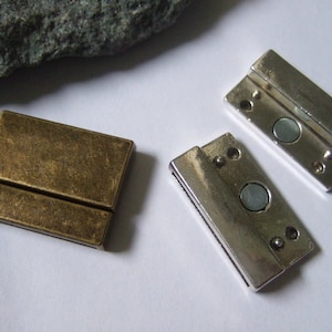 May include: Three rectangular magnetic clasps are shown. One is antique brass, the other two are silver-toned. Each clasp features a magnetic disc for secure closure. These clasps are suitable for jewellery making and various craft projects.