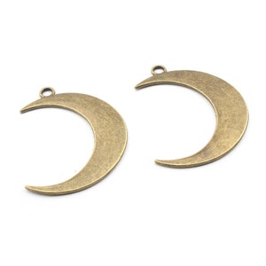 May include: Two antique gold-toned crescent moon charms with a loop at the top for hanging.