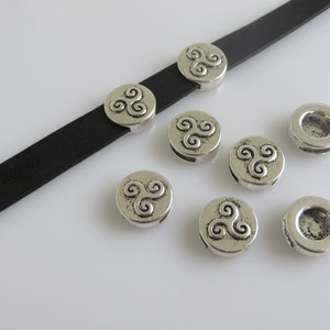 May include: Silver-toned metal beads with a Celtic knot design. The beads have a hole in the centre for threading onto a cord or chain.