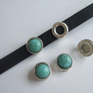 May include: Four silver-toned metal round beads with turquoise cabochon stones. The beads are on a black leather strap.