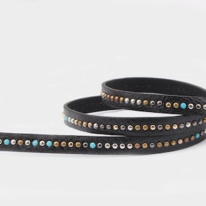 May include: Black leather trim with a row of silver, gold, and turquoise coloured studs.