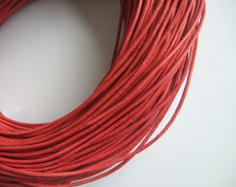 Op de afbeelding: Een spoel met rood lederen koord. Het koord is strak gewikkeld en ongeveer 6 mm dik.