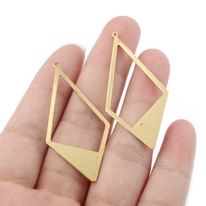 May include: Two gold-coloured metal earring blanks in the shape of a diamond with a smaller diamond cut out in the centre. The blanks have a hole at the top for attaching earring wires.