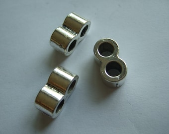 May include: Three silver metal bead spacers with two holes each. The spacers are shaped like a figure eight.