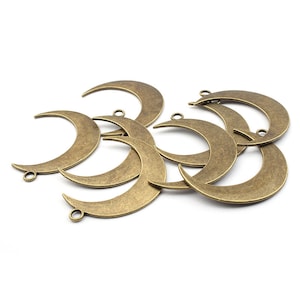 May include: A group of eight antique gold-toned metal crescent moon charms with a hole at the top for hanging.