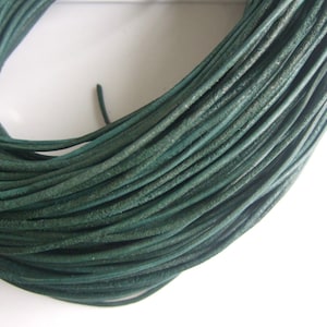 May include: A spool of dark green leather cord. The cord is tightly wound and has a smooth, slightly textured surface.