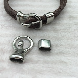 May include: Silver-toned metal bracelet clasp with a loop and a rectangular end cap. The clasp is designed for leather bracelets.