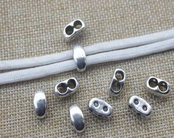 May include: Silver metal cord ends with a double loop design. The cord ends are shown on a white cord.