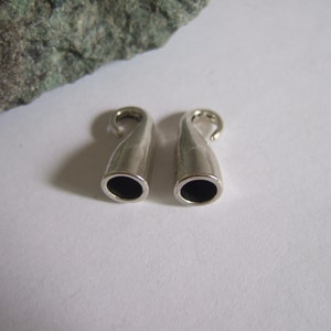 May include: Two silver-toned metal cord ends with a hook on one end and a small hole on the other end.