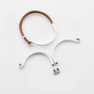 May include: A brown leather bracelet with silver metal clasps and a hook closure.