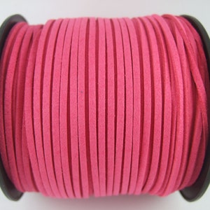 May include: A spool of pink suede cord, wound tightly around a black plastic bobbin.