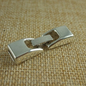 May include: Silver-toned metal clasp for jewelry making. The clasp is made of two pieces that snap together.
