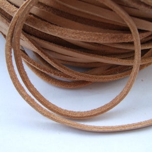 Puede incluir: Primer plano de un carrete de cordón de cuero marrón claro. El cordón es liso y flexible, con una superficie ligeramente texturizada.