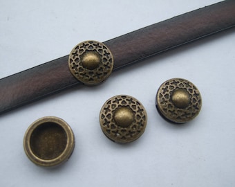 Könnte beinhalten: Vier antike, goldfarbene, runde Dekorknöpfe aus Metall mit einem erhabenen Zentrum und filigranen Designs. Die Knöpfe befinden sich auf einem braunen Lederband.
