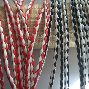 May include: Close-up of braided leather cord in red and white, and black and white colour combinations. The cord is woven in a diamond pattern.