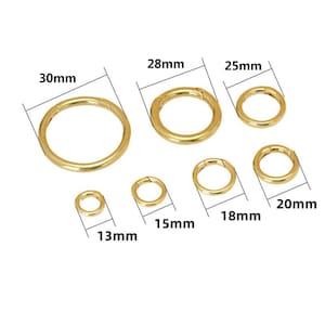Könnte beinhalten: Eine Auswahl goldfarbener Federringverschlüsse in verschiedenen Größen. Der größte Ring hat einen Durchmesser von 30 mm, die anderen messen 28 mm, 25 mm, 20 mm, 18 mm, 15 mm und 13 mm. Diese Verschlüsse eignen sich für Schmuckherstellung und Bastelarbeiten.