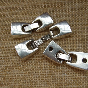 以下が含まれることがあります： ジュエリー作りのための3つの銀色の金属製留め具。留め具は長方形で、ヒンジのデザインと両側に小さな穴があります。
