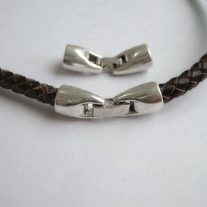 May include: A brown leather braided bracelet with silver-toned magnetic clasps.