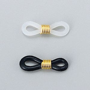 Pu&ograve; includere: Due paia di terminali per aste di occhiali, uno bianco e uno nero, con un connettore in metallo dorato al centro.