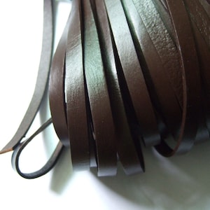 May include: A bundle of brown leather cords, approximately 6 mm wide, arranged in a fan shape.