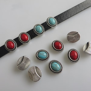 May include: A set of oval-shaped metal embellishments with turquoise and red stones. The embellishments have a silver finish and a decorative border.