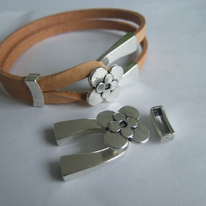 Peut inclure: Un bracelet en cuir marron avec un fermoir en forme de fleur argenté et un fermoir à bascule en forme de fleur argenté.