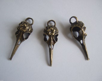 May include: Three antique bronze bird skull charms with floral details. Each charm has a loop at the top for attaching to jewelry or other crafts.