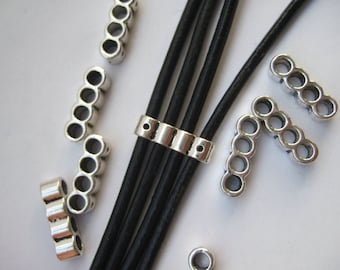 May include: Silver metal cord ends with multiple round holes for threading leather cords. The cord ends are shown on a black leather cord.