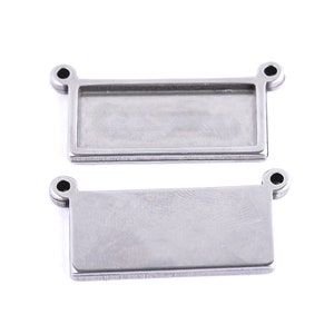 May include: Two silver metal rectangular tags with rounded corners and two small holes at the top. The tags are blank and ready for personalisation.