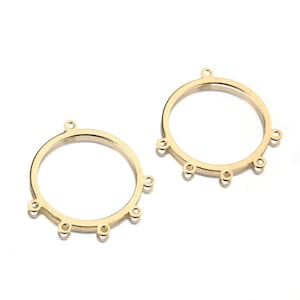 Puede incluir: Dos aros de metal dorado con cinco anillos de salto unidos a cada aro. Los aros son circulares y tienen un acabado liso.