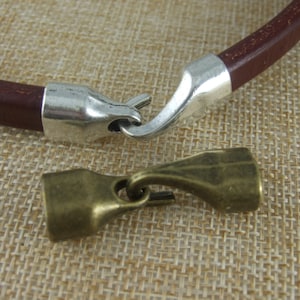 May include: A brown leather bracelet with silver and brass clasps. The bracelet has a hook and loop closure.