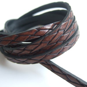 May include: Brown leather cord with a braided design and black edging.