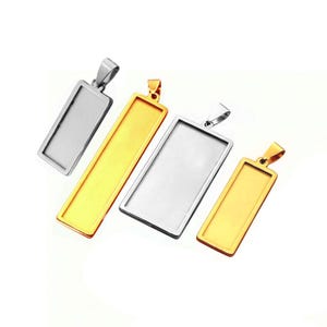 Pode incluir: Quatro pingentes retangulares de metal com argolas, incluindo dois acabamentos em tom prateado e dois em tom dourado. Estes componentes de joalharia possuem uma área central plana e rebaixada para inserções personalizadas ou decorações.