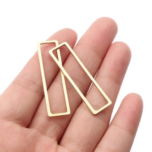 May include: Two gold-colored metal rectangular earring blanks. The blanks are open on one side and have a smooth, polished finish.