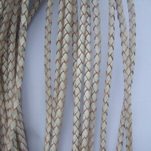 May include: A close-up of a bundle of white leather cord, braided in a diamond pattern.