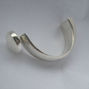 May include: A silver ring with a round, smooth top and a curved band.