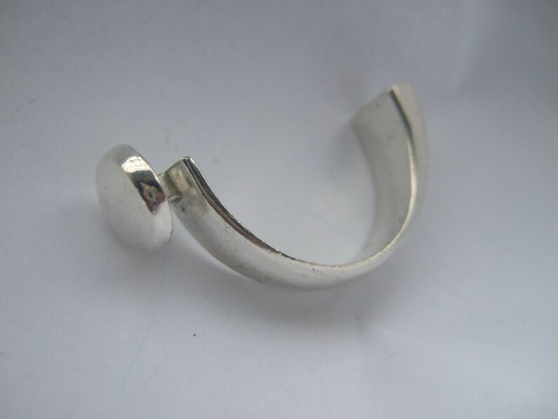 May include: A silver ring with a round, smooth top and a curved band.
