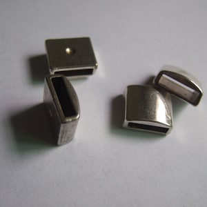 May include: Four silver metal clasps for jewellery making. Two are square and two are rounded.