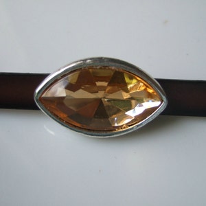 May include: A brown leather strap with a silver-toned, marquise-shaped, clear orange rhinestone embellishment.