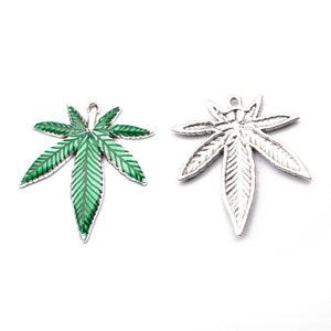 May include: A silver charm in the shape of a marijuana leaf with green enamel. The back of the charm is plain silver.