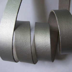 Puede incluir: Primer plano de un cordón de cuero plateado, mostrando la textura y el brillo del material.