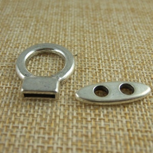 May include: Two silver metal toggles, one with a loop and a rectangular base, the other with two holes.