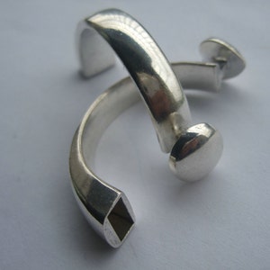 May include: Two silver rings, one with a square opening and the other with a rounded end.