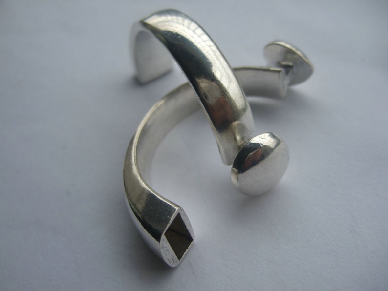 May include: Two silver rings, one with a square opening and the other with a rounded end.