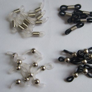 May include: Assortment of clear and black eyeglass or sunglass temple tips. Some tips have a metal spring, while others have a metal bead.
