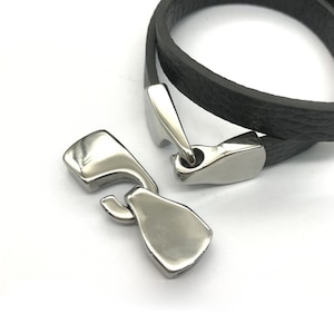 May include: A black leather bracelet with a silver clasp. The bracelet is double-layered and has a simple design.