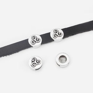 May include: Three silver-toned metal beads with a black swirl design. The beads are on a black leather strap.