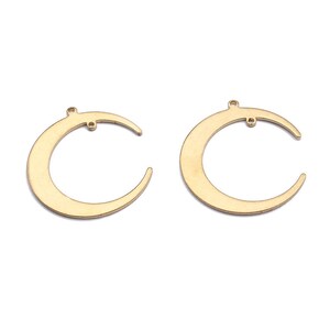 Puede incluir: Dos abalorios de metal en forma de media luna de color dorado con un pequeño bucle en la parte superior para sujetarlos a joyas u otras manualidades.